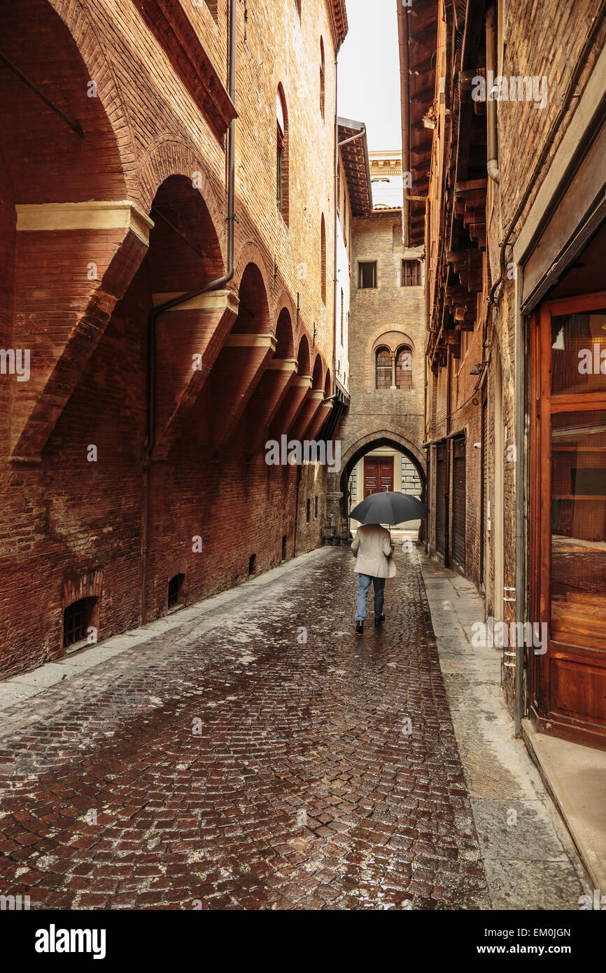 A lone passerby with an umbrella on a narrow street in the old city of Bologna Italy Stock Photo