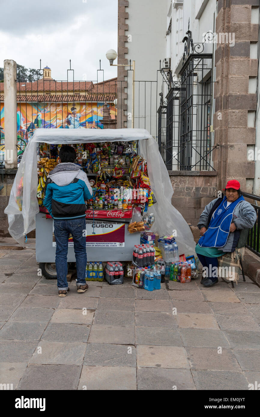 Peru, Cusco.  Young Man Stopping at a Streetside Snack Stand. Stock Photo