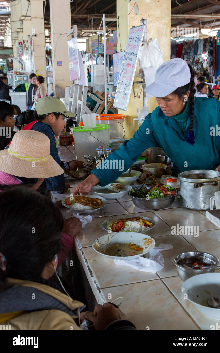 Peru, Cusco, San Pedro Market.  Cook Serving a   Customer Eating in the Food Court Area of the Market. Stock Photo
