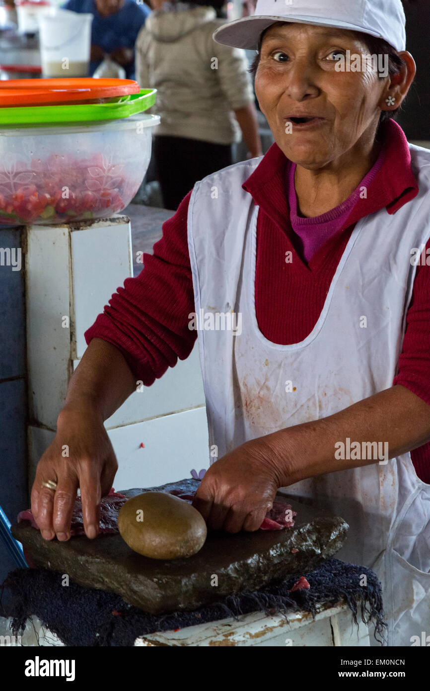 Peru, Cusco.  San Pedro Market.  Woman Pounding Meat with a Stone to Tenderize it. Stock Photo