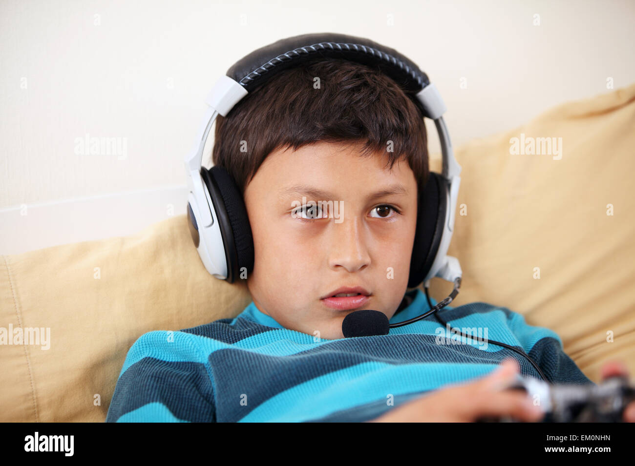 Young boy concentrating on playing video game with his friends with headset and microphone with copy space Stock Photo