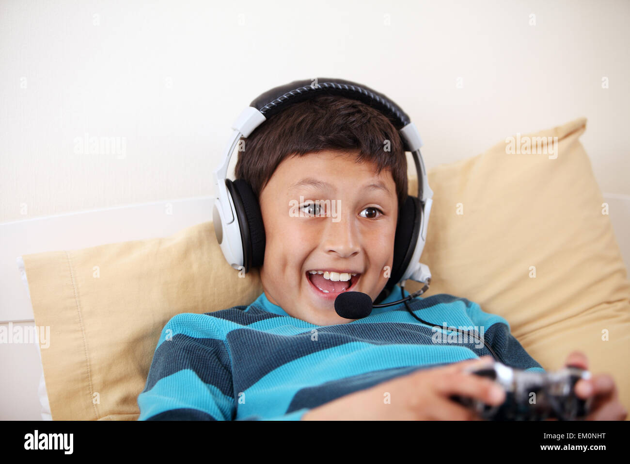 Young happy boy playing video game with his friends with headset and
