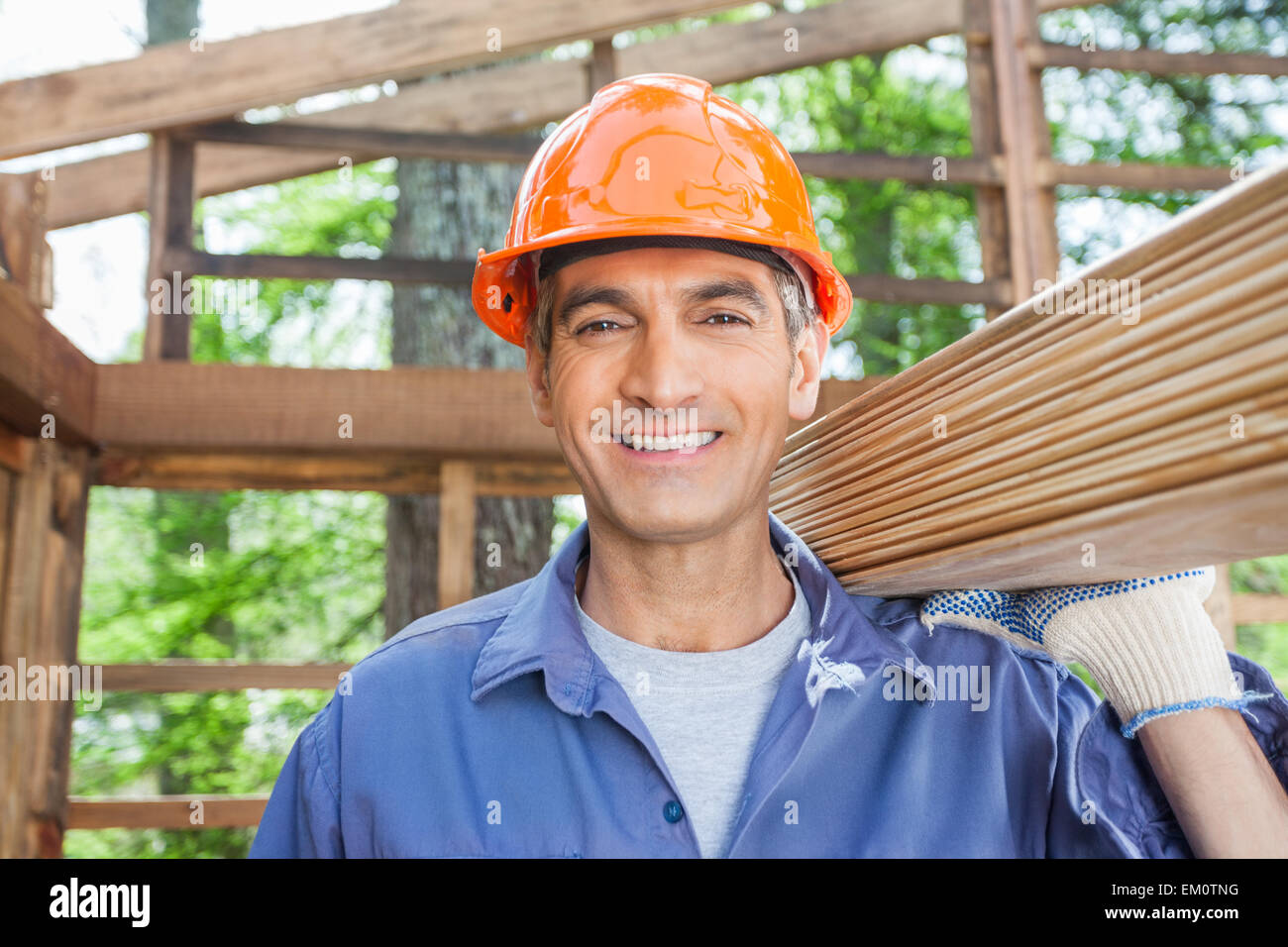 Happy Construction Worker Carrying Wooden Planks Stock Photo - Alamy