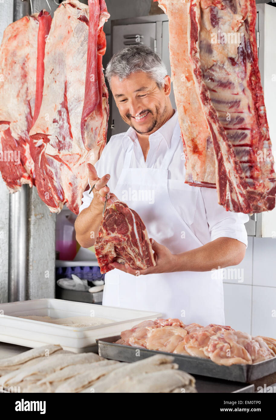 Butcher Holding Raw Meat With Hook Stock Photo