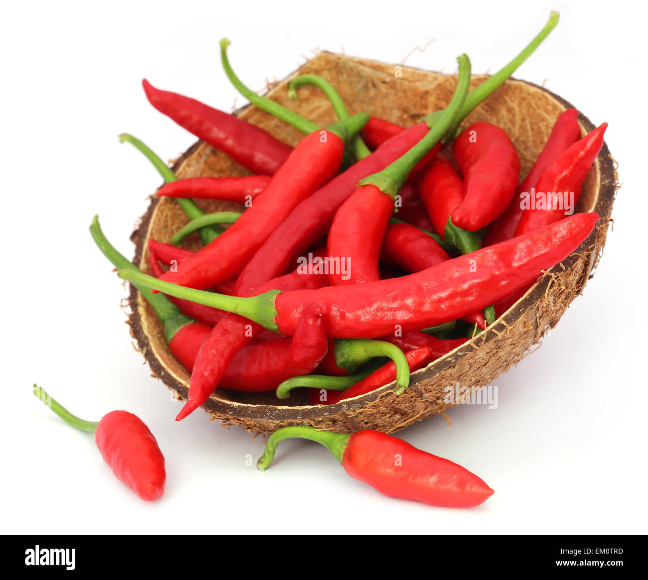 Red chili peppers in a coconut shell over white background Stock Photo
