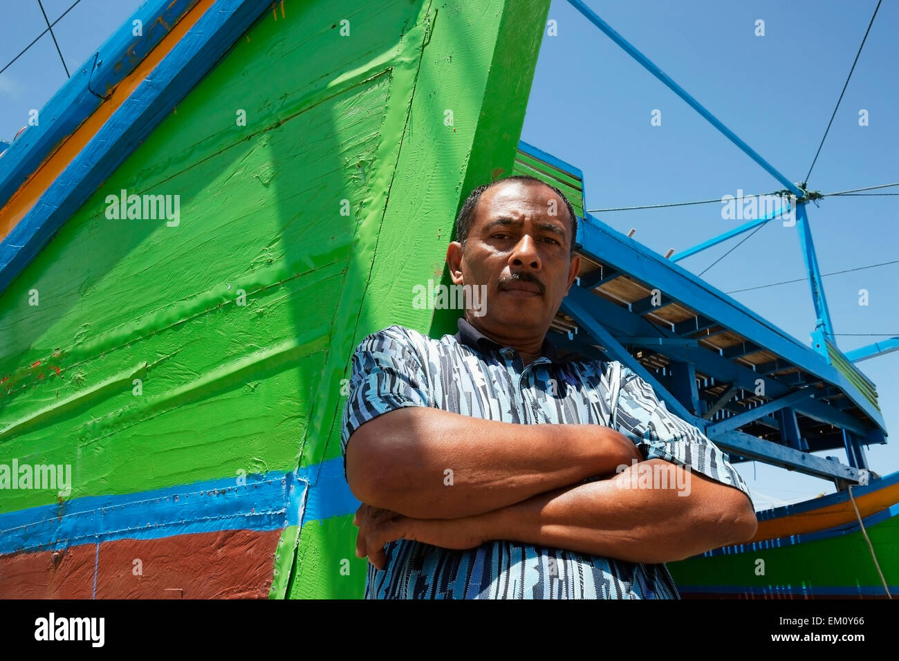A fisherman stands with his colourful fishing boat in Lhok Seudu village; Aceh Province, Sumatra, Indonesia Stock Photo