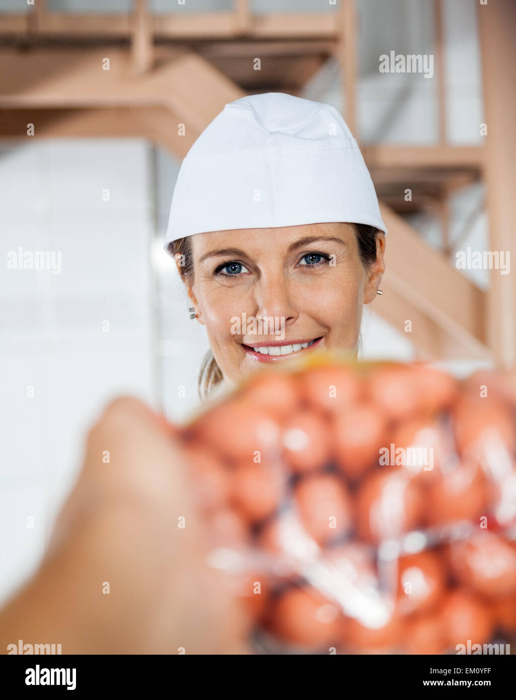 Happy Butcher Selling Packed Sausages To Customer Stock Photo