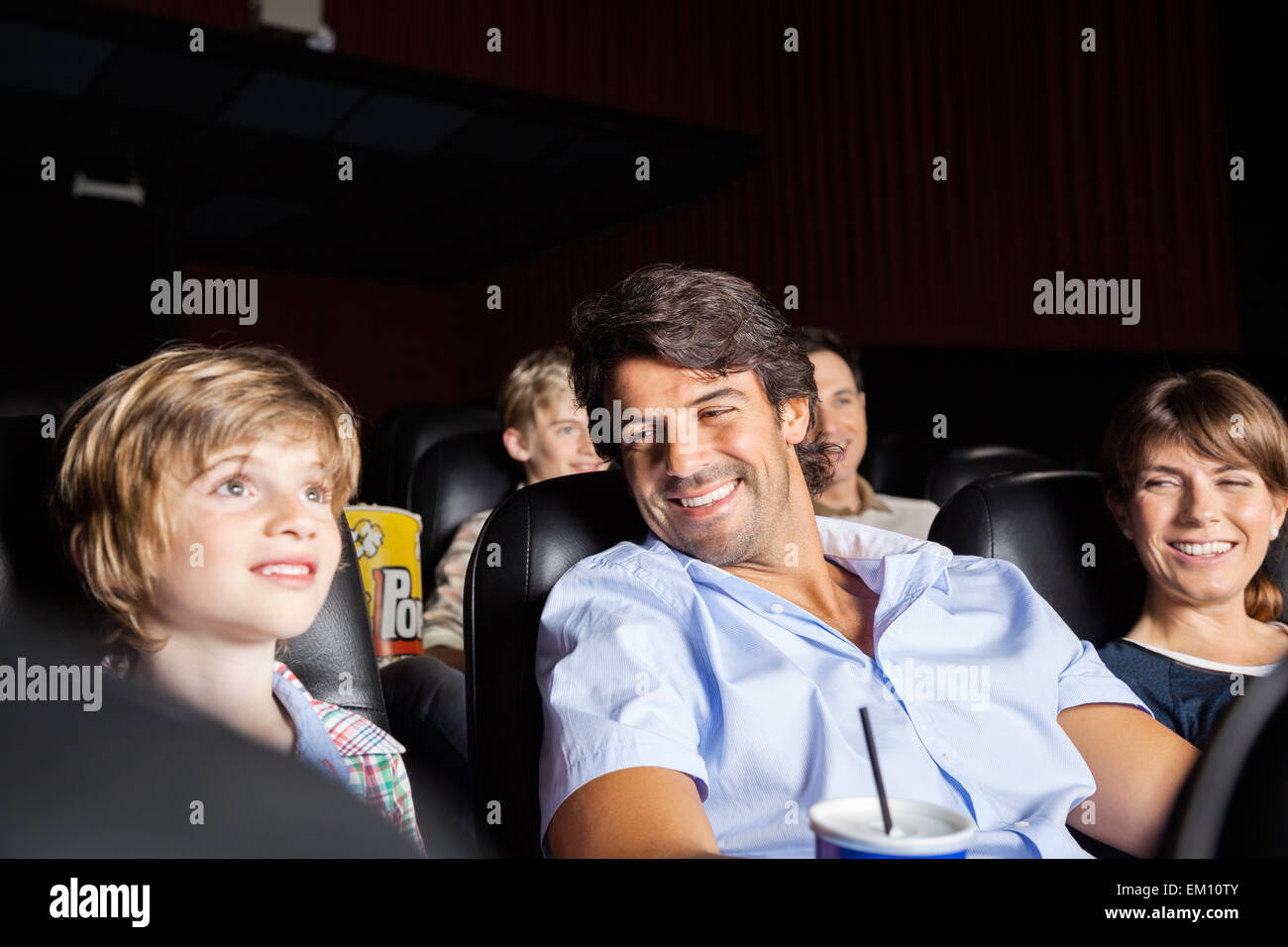 Happy Family Watching Movie In Theater Stock Photo