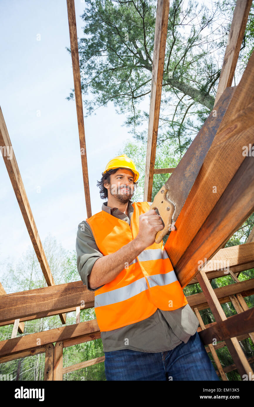 Worker Cutting Wood With Handsaw At Construction Site Stock Photo