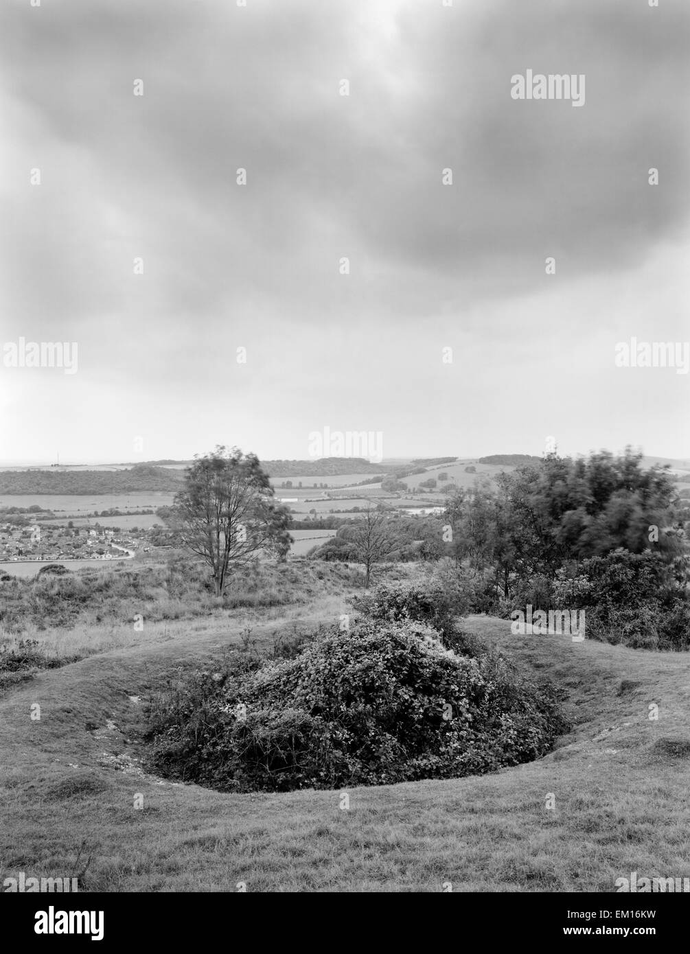 Looking W to South Downs & coast over one of 200+ partly-filled shafts of Neolithic flint mines surrounded by Iron Age ramparts of Cissbury Ring. Stock Photo