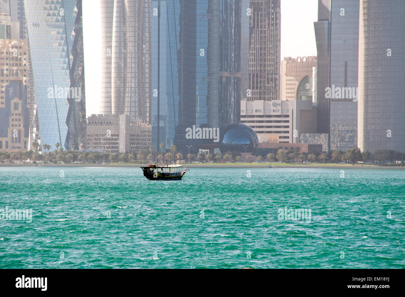 A dhow boat plows the waters of the Arabian Gulf near the skyline of Doha, the capital of Gulf nation of Qatar. Stock Photo