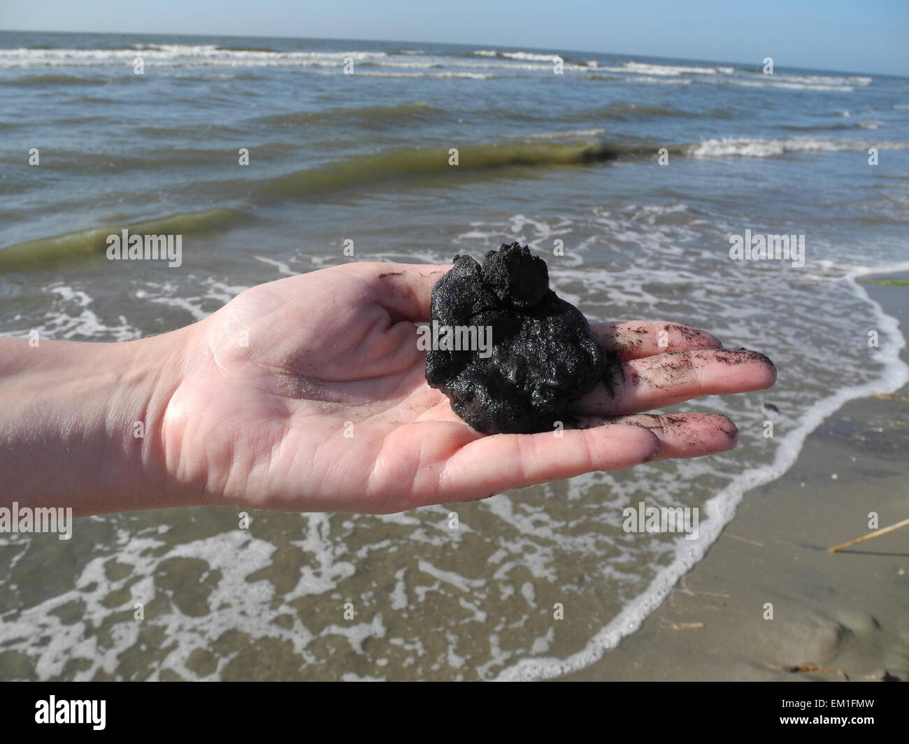 Mexico, US. 8th Apr, 2015. Alisha Renfro of the National Wildlife Federation holds a lump of tar in her hand on the Isle Grande Terre in the Gulf of Mexico, US, 8 April 2015. 20 April 2015 marks the 5th anniversary of the Deepwater Horizon catastrophe in the Gulf of Mexico which took place on 20 April 2010. Photo: Johannes Schmitt-Tegge/dpa/Alamy Live News Stock Photo