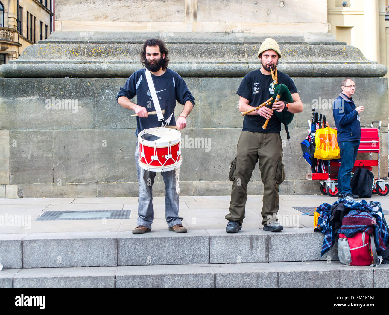 Street musicians play a drum and bagpipes at the foot of Grey's Monument in Newcastle UK. Stock Photo