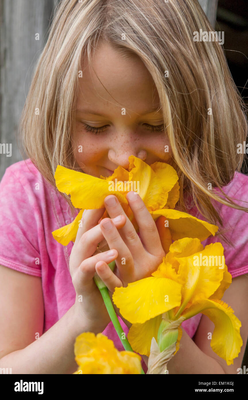 girl smelling yellow Iris flowers Stock Photo