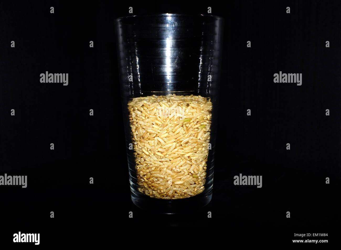 A glass half full/half empty of photographed against a black background