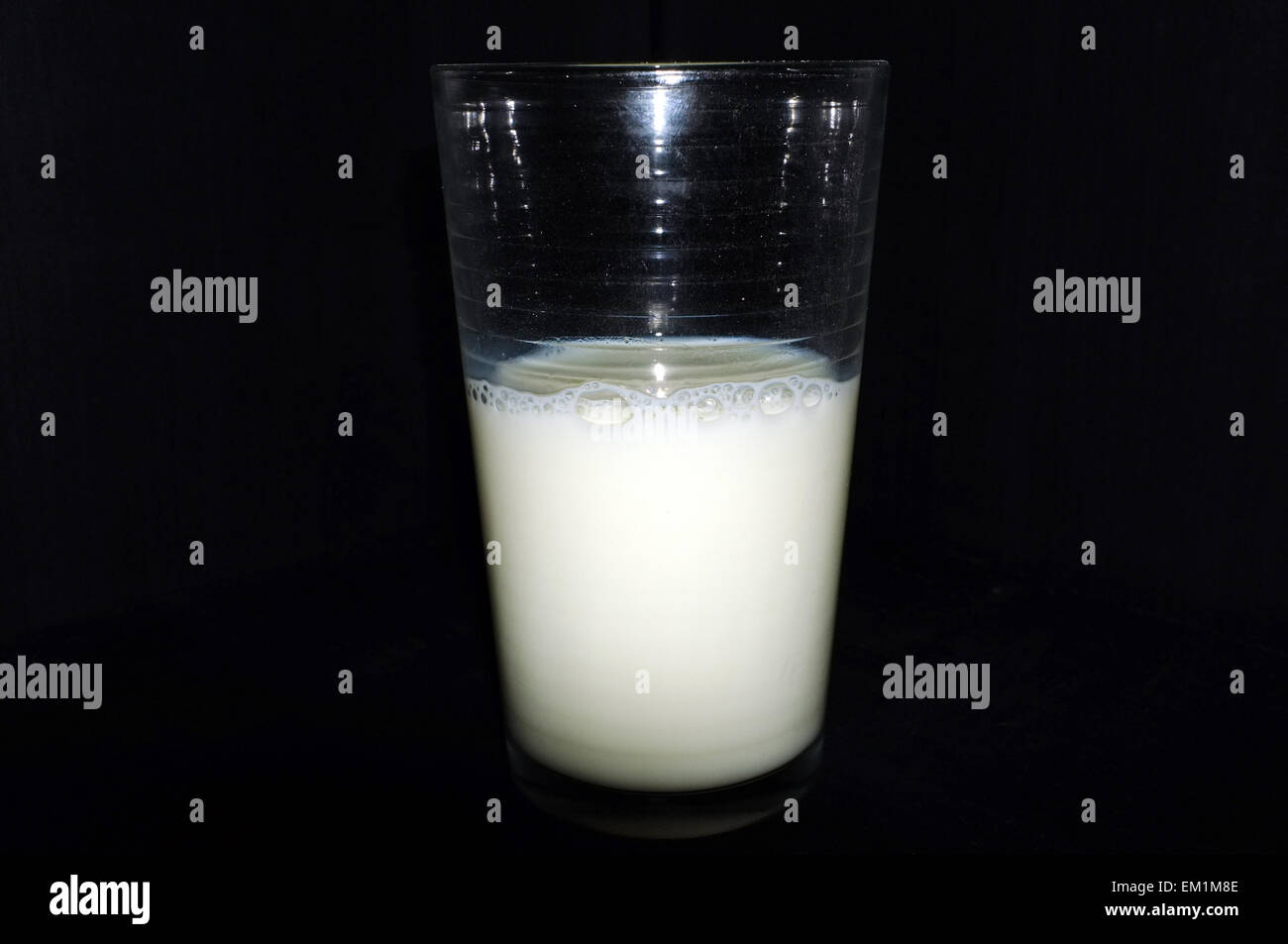 A glass half full/half empty of milk shells against a black background. Stock Photo