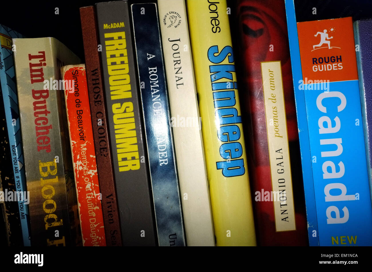 A collection of books stored in a row on a black bookshelf Stock Photo