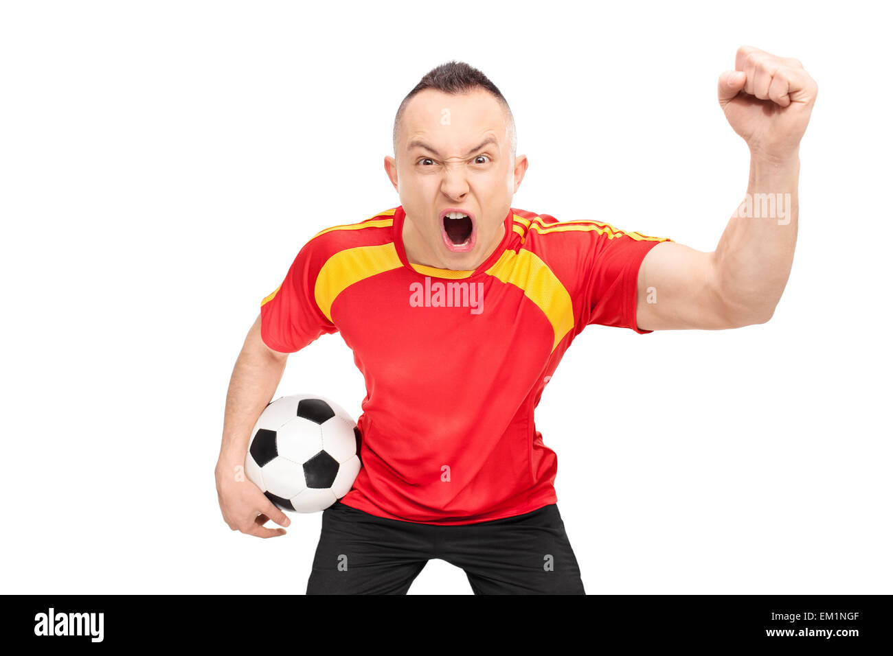 Ecstatic young sports fan in a red football jersey holding a football and cheering isolated on white background Stock Photo