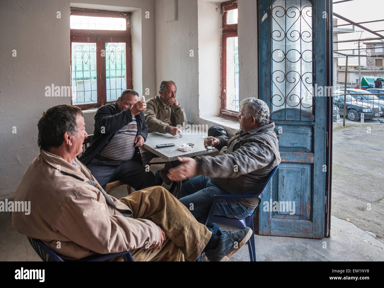 Men drinking raki in a bar in the village of Xarre on the Vrina plain at Butrint National Park, Southern Albania. Stock Photo