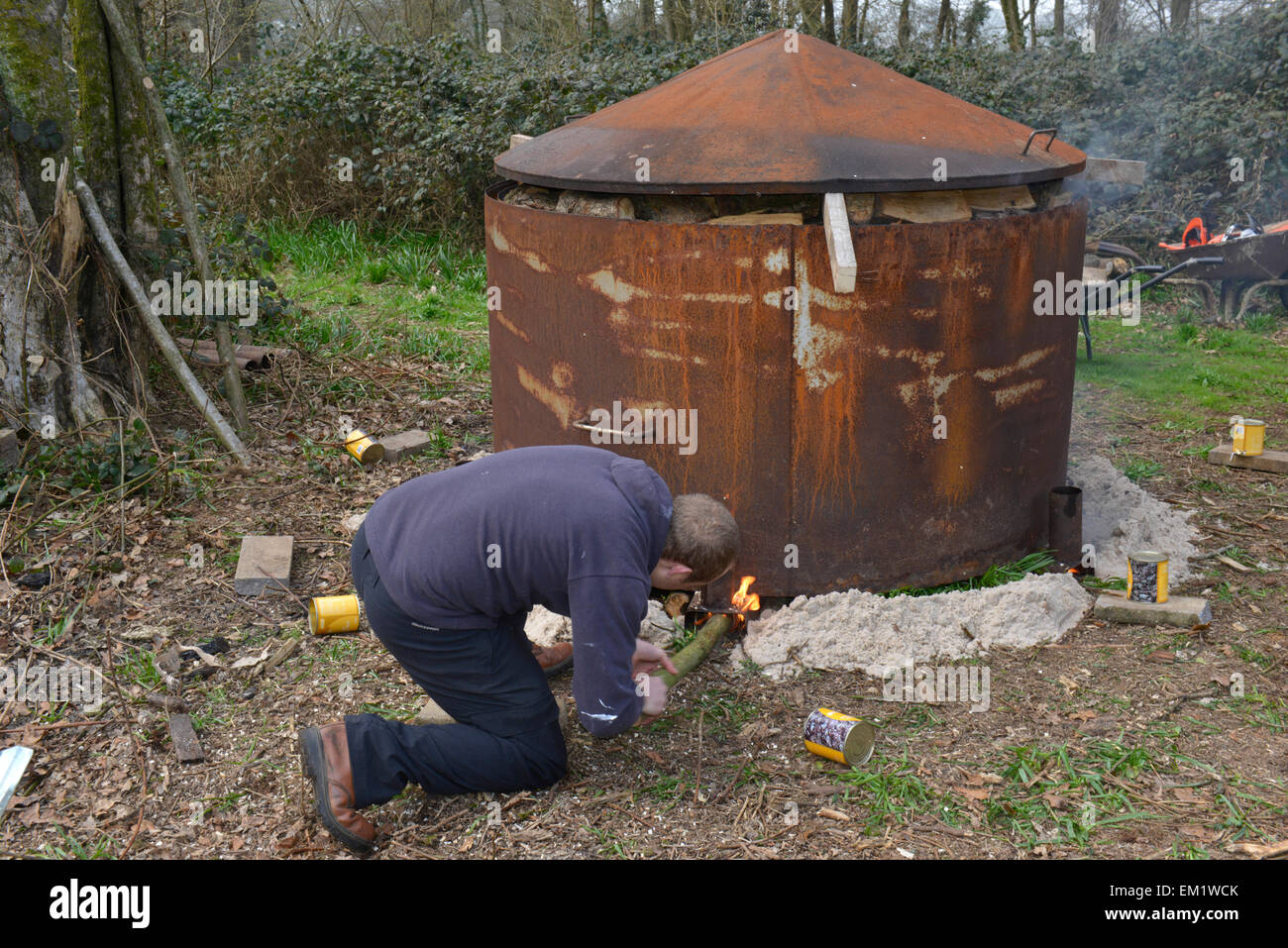 A charcoal kiln being lit in a deciduous woodland in southern England Stock Photo