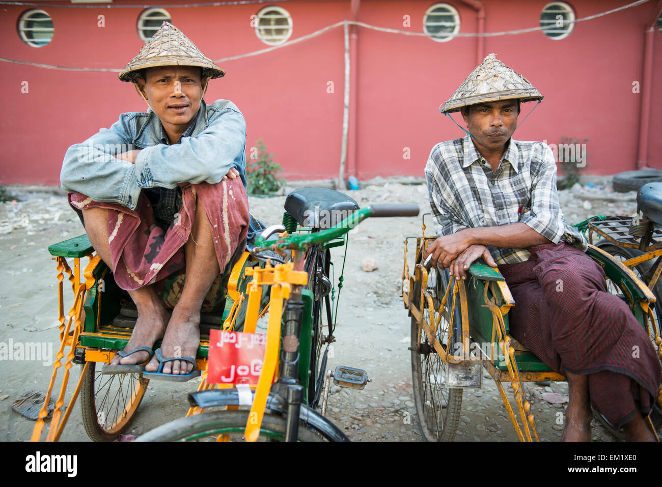 Two men wearing conical hats sit in their pedicabs; Sittwe, Rakhine State, Burma Stock Photo