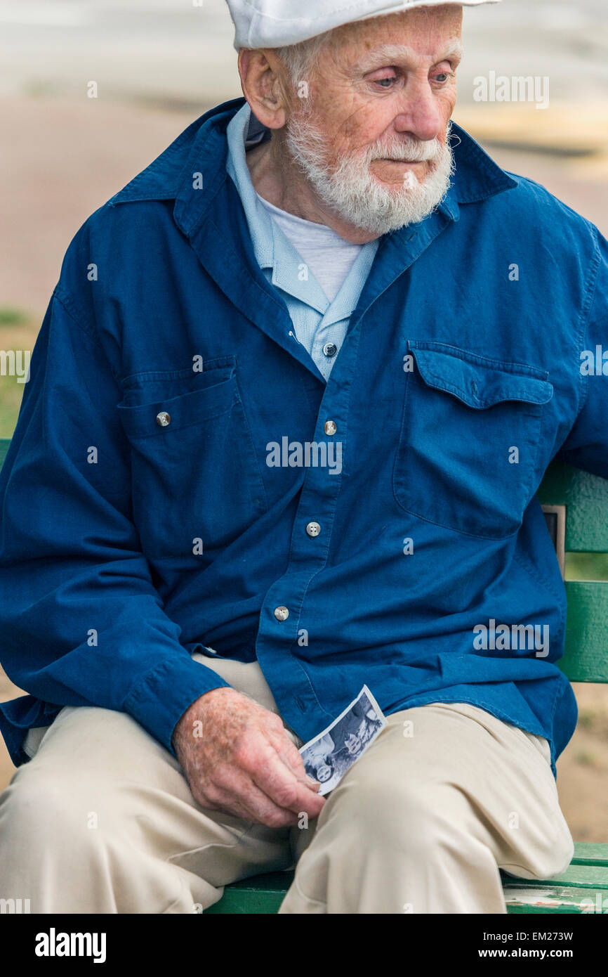 A elderly man sitting alone on park bench with sadness Stock Photo - Alamy