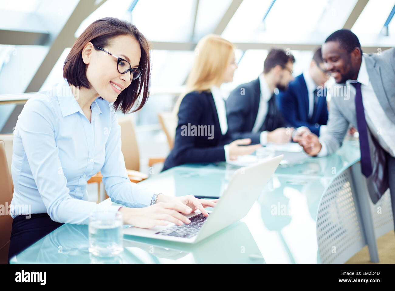Pretty employee typing on laptop in working environment Stock Photo - Alamy
