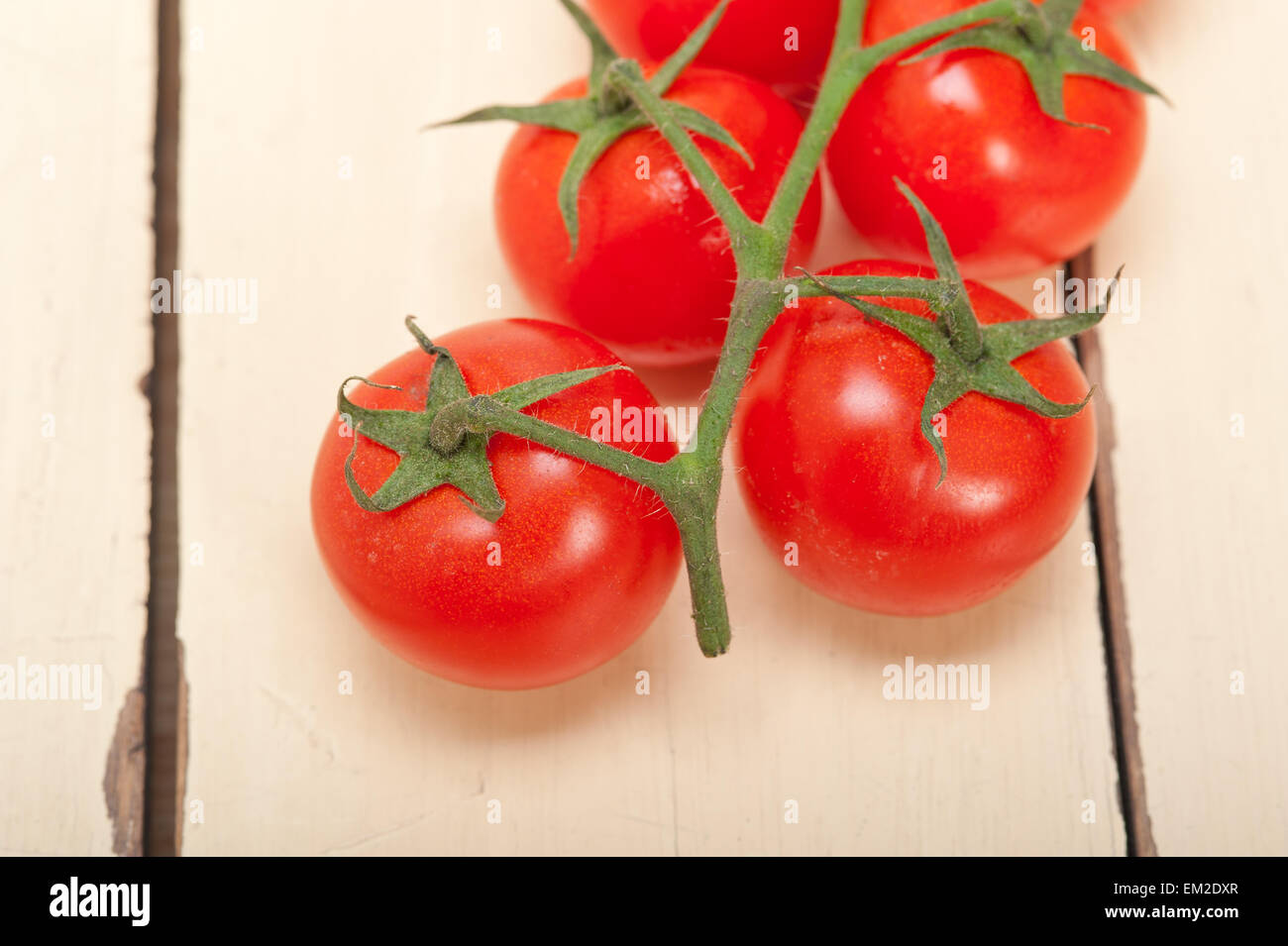 fresh cherry tomatoes on a cluster over rustic wood table Stock Photo ...