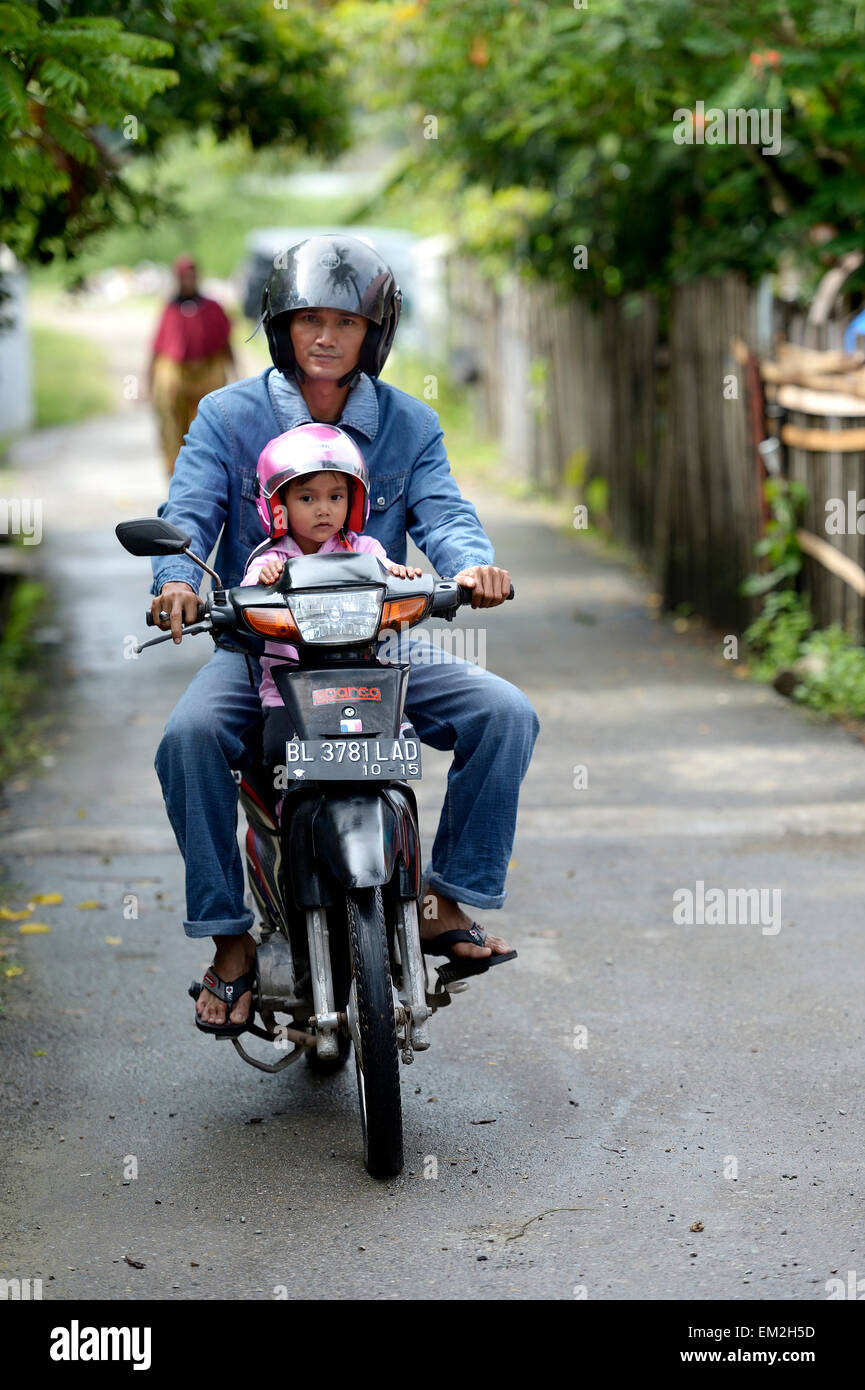 Man with child on a motorcycle, Gampong Nusa village, Aceh, Indonesia Stock Photo