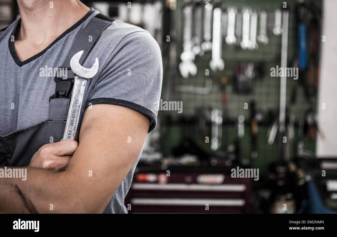 Mechanic holding a wrench. Close-up at a garage with tools on the background. Stock Photo