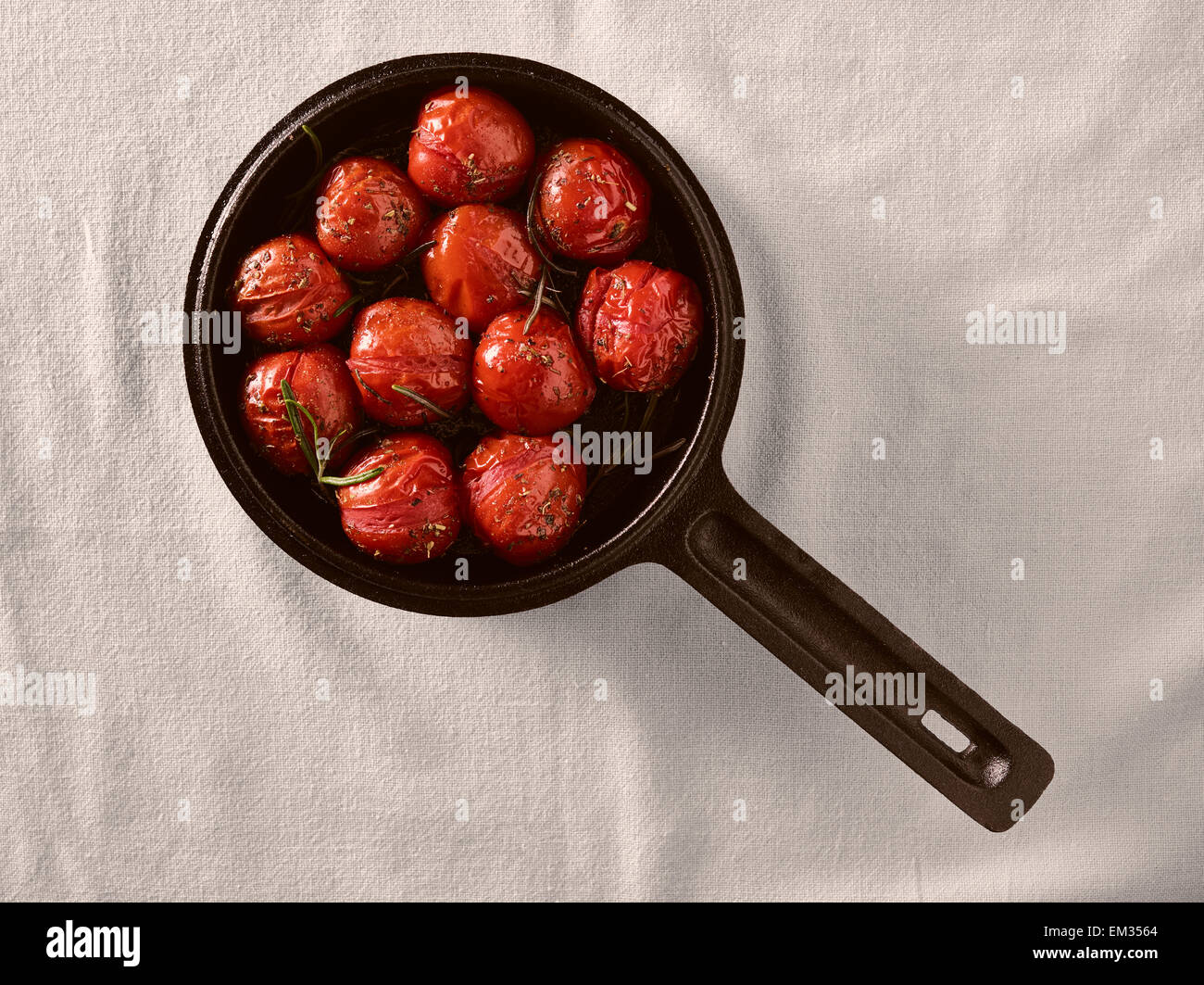 Grilled cherry tomatoes in a small cast iron pot, rosemary Stock Photo