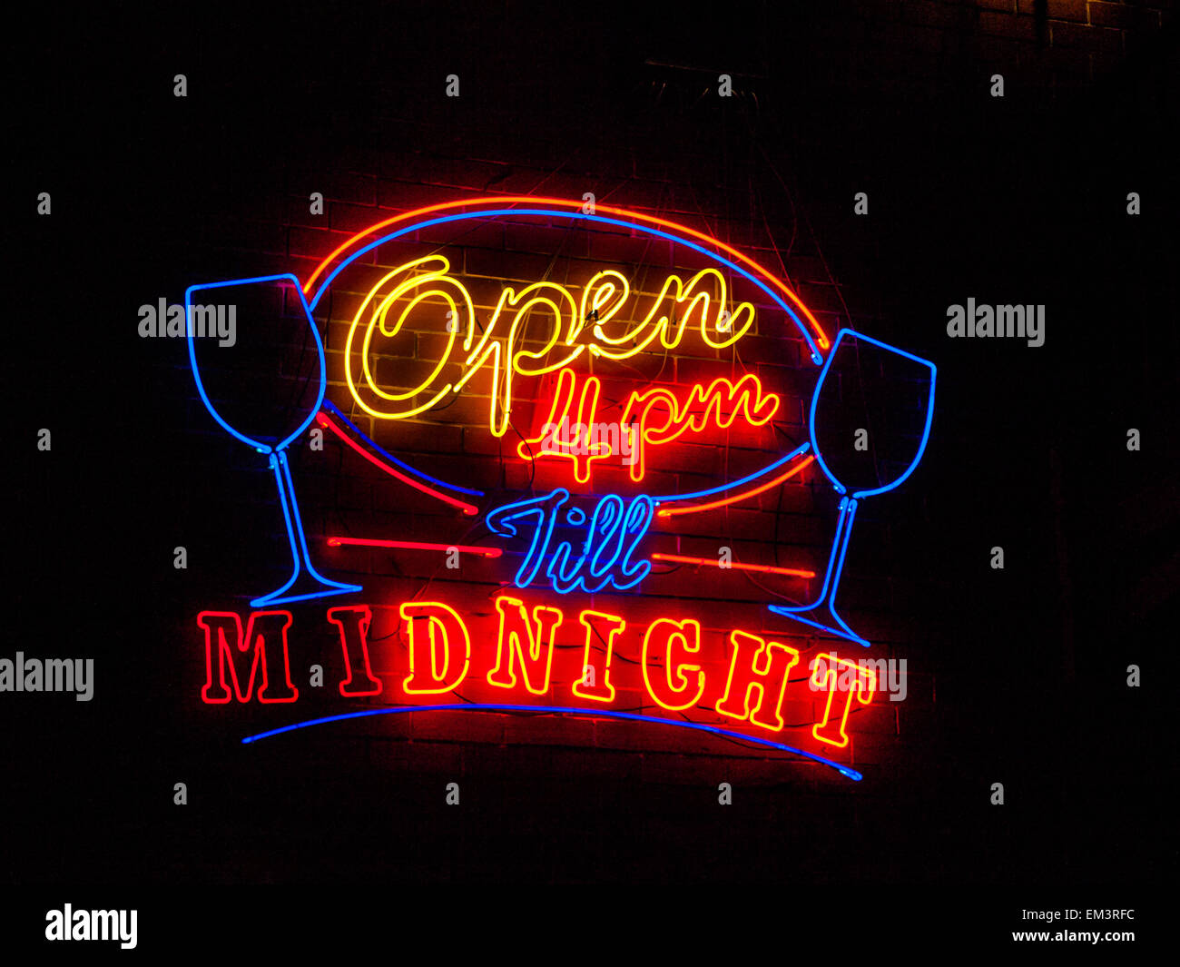Red, green, purple and yellow neon sign of the words 'open 4pm till MIDNIGHT' on a black background. Stock Photo