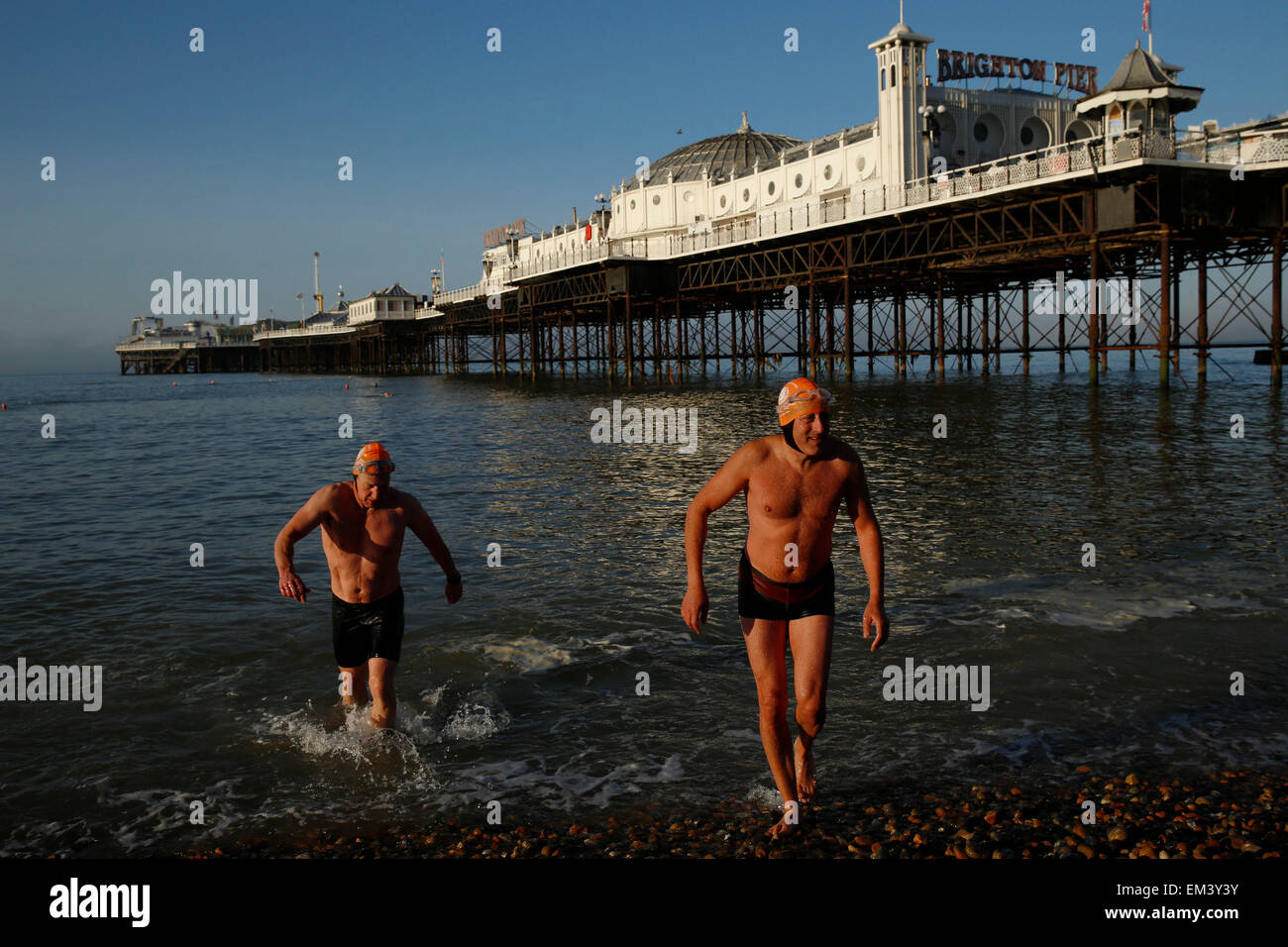 Members of Brighton Swimming Club get out of the sea after a morning swim in the sun by Brighton Pier in East Sussex Stock Photo