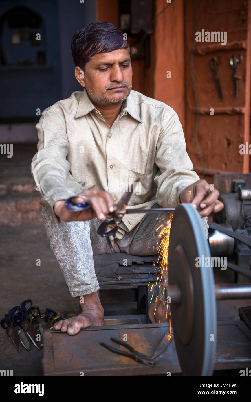 A man grinding the blades of a pair of scissors in Jaipur, Rajasthan, India Stock Photo