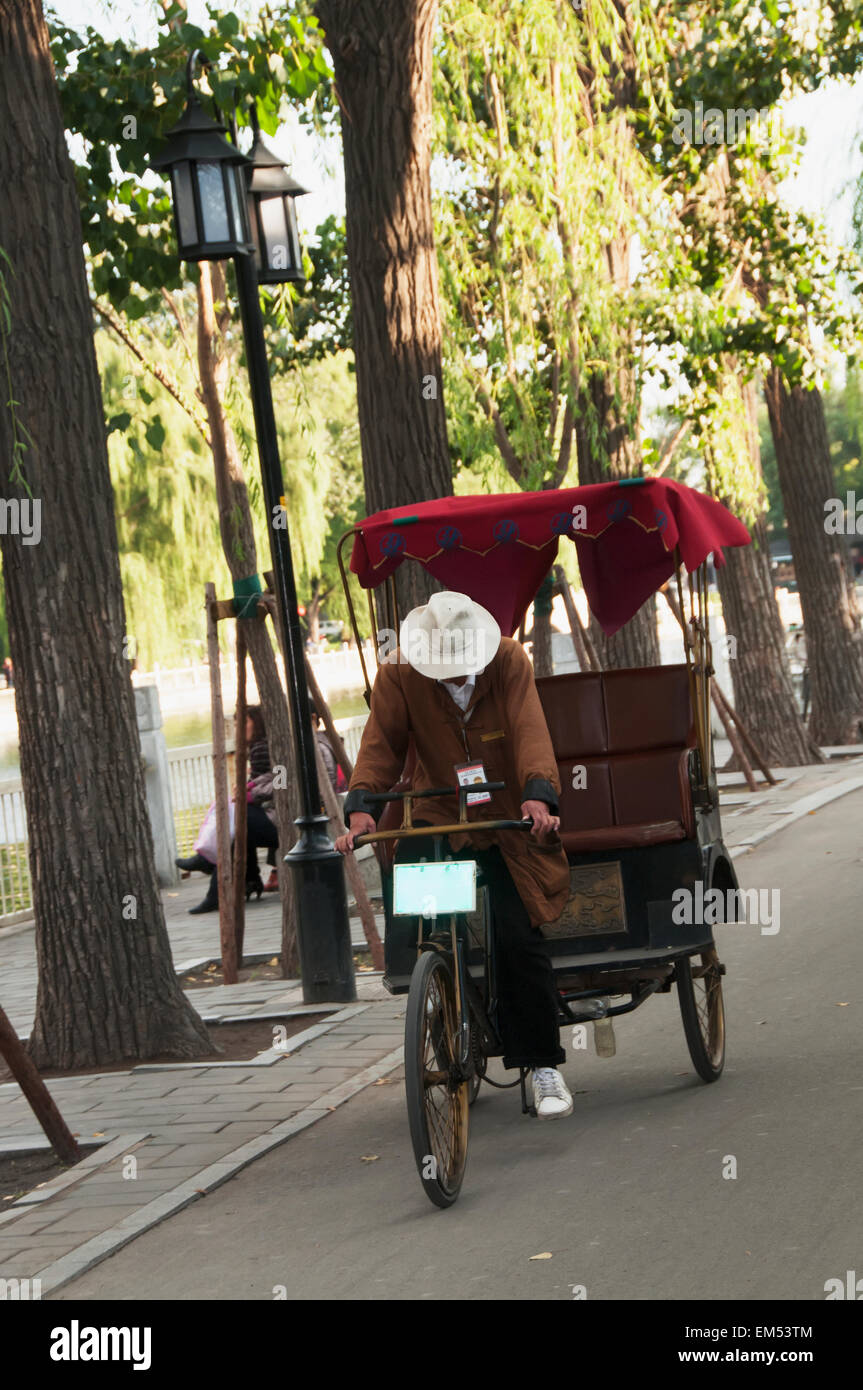 China, Beijing, Rickshaw and driver going down street Stock Photo