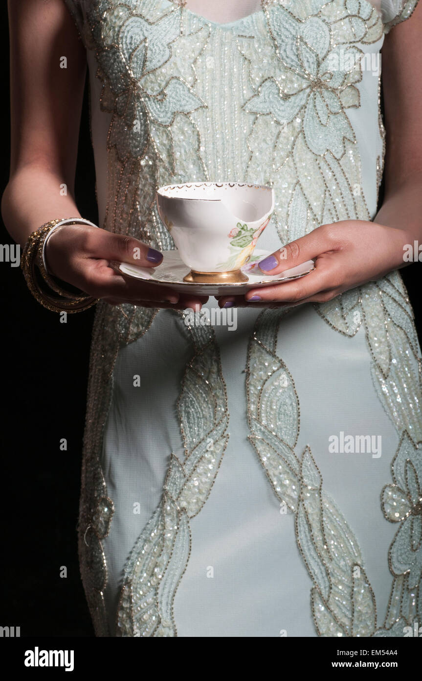 Young woman holding a broken teacup Stock Photo