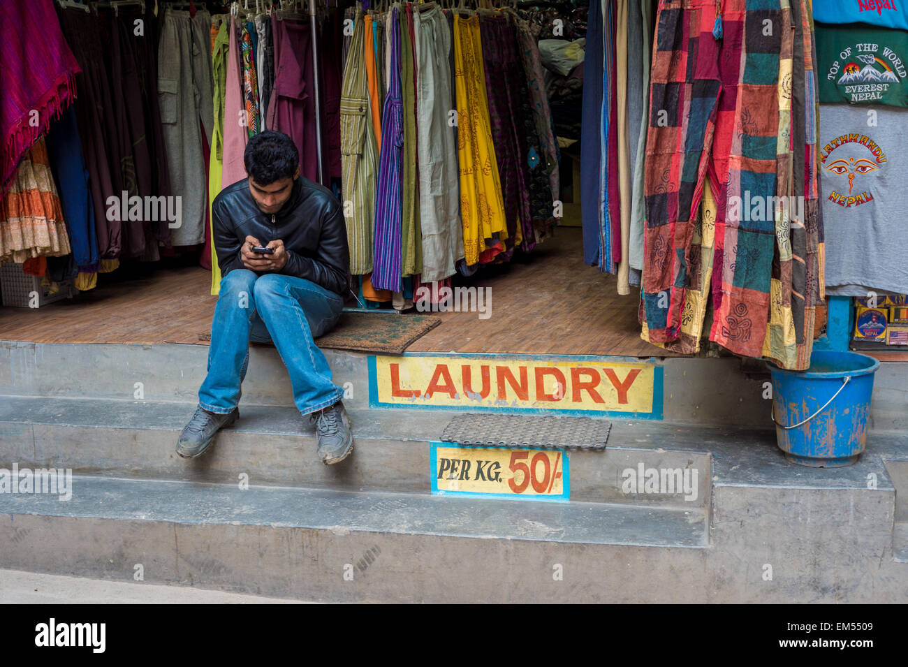 Nepali seller texting on his cell phone Stock Photo