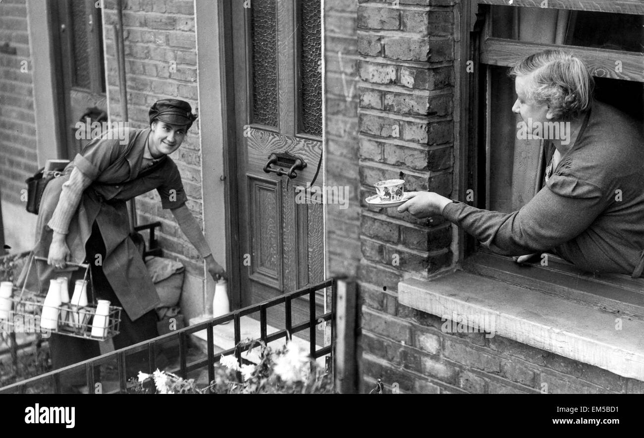 May Pearce, a milk girl, being given a cup of tea by her mother. 29th November 1942. Stock Photo