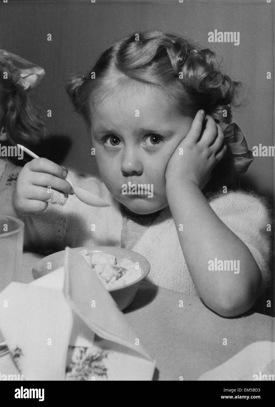 Anne Page, 4, faces a child's saddest Christmas party moment. She has just realised she is absolutely full up. And here comes a second dish of Jelly during a party given by U.S. Embassy staff for London Children. 18th December 1951 Stock Photo