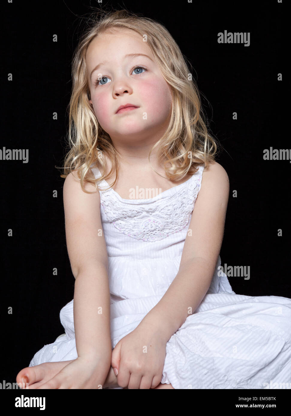 Portrait of a contemplative young girl on black background. Stock Photo