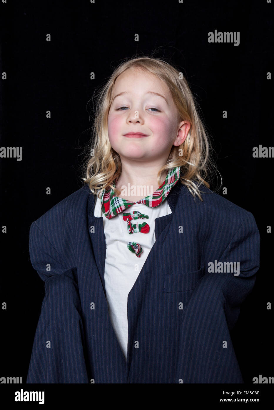 Portrait of a young girl dressing up in adult clothes on a black background. Stock Photo