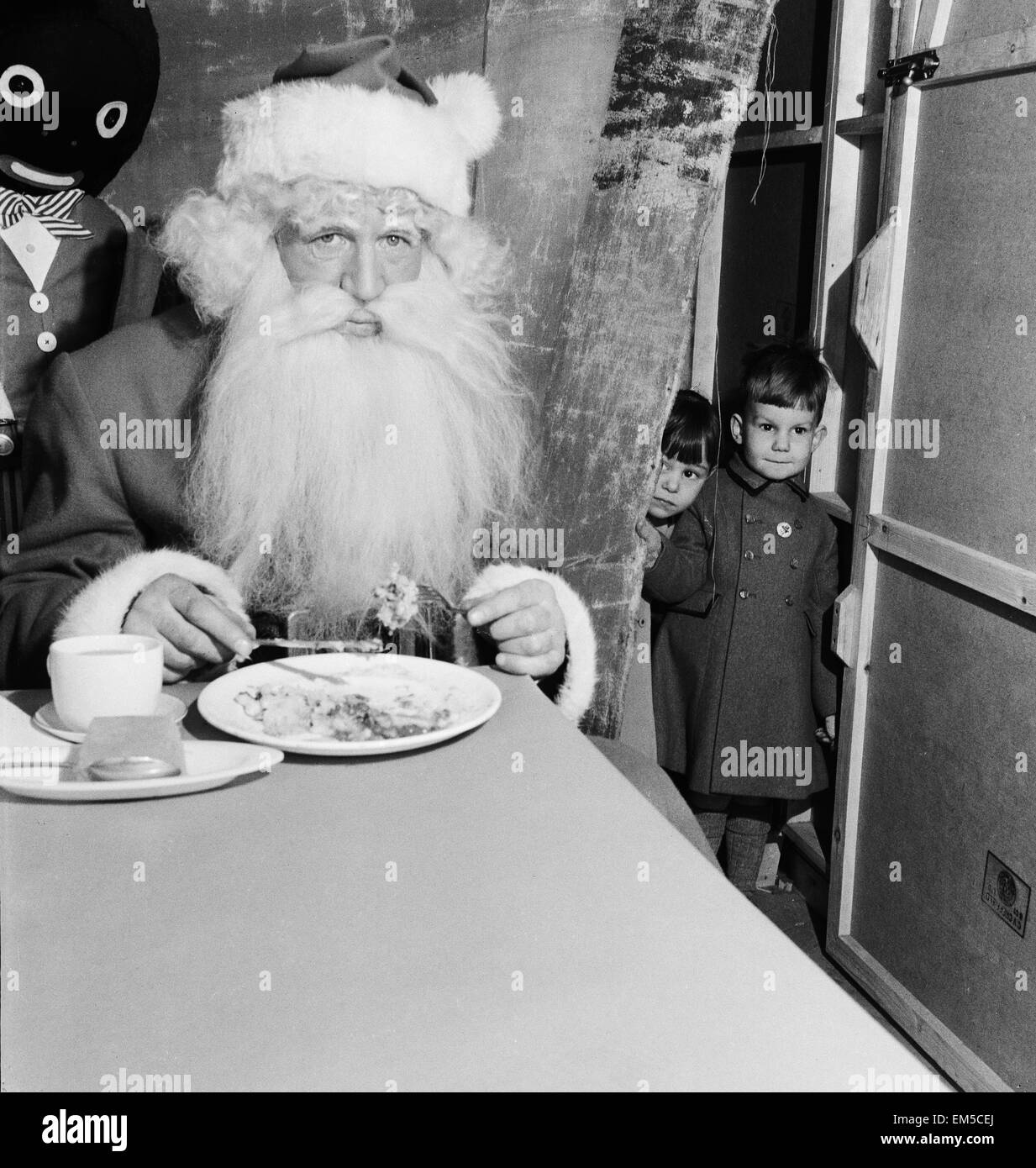 Children watching Father Christmas eating his dinner. 29th December 1955. Stock Photo