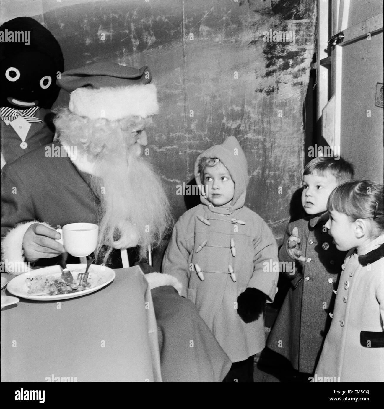 Children watching Father Christmas eating his dinner. 29th December 1955. Stock Photo
