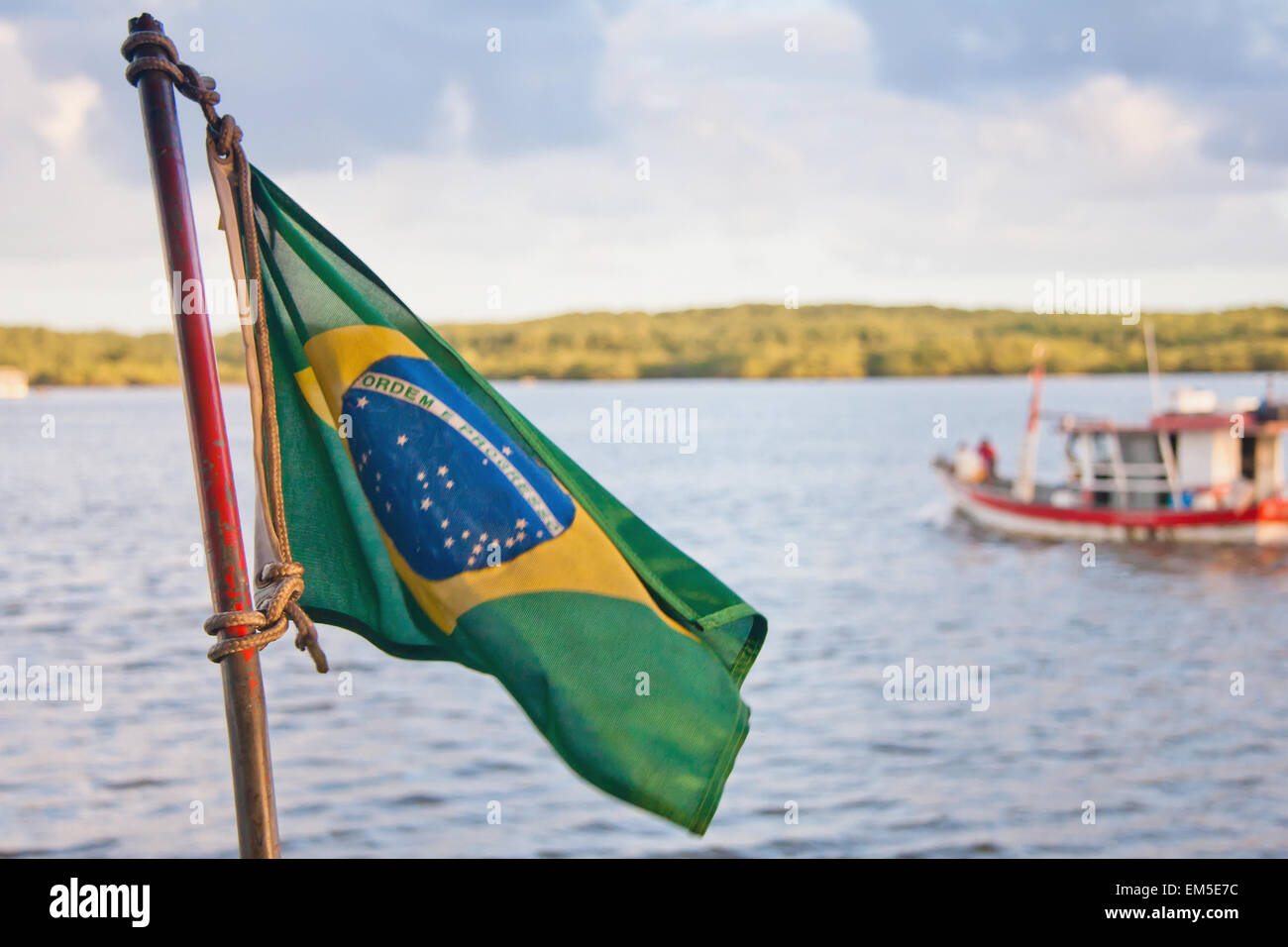 Brazilian flag with boat in water in background; Puerto Seguro, Brazil Stock Photo