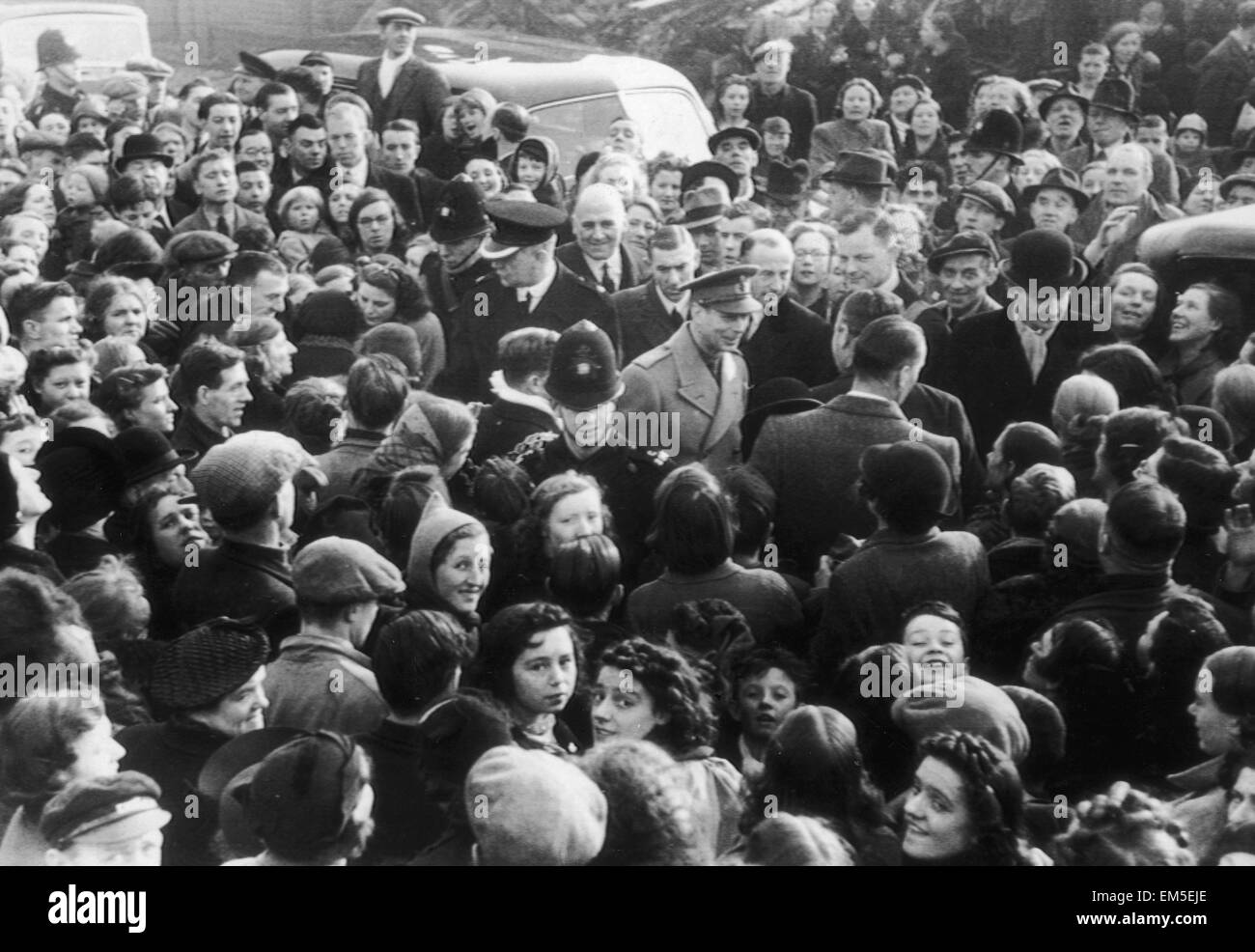 King George VI surrounded by a crowd of enthusiastic people welcoming him to the bomb damaged city of Birmingham following an air raid. December 1940. Stock Photo