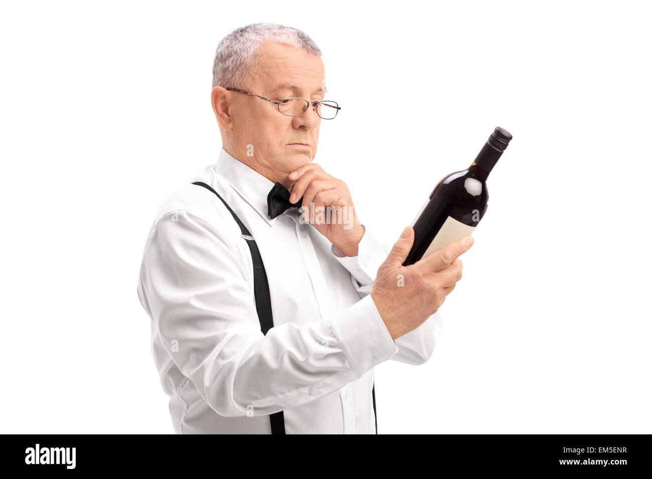 Elegant senior with glasses reading the label on a bottle of a red wine isolated on white background Stock Photo