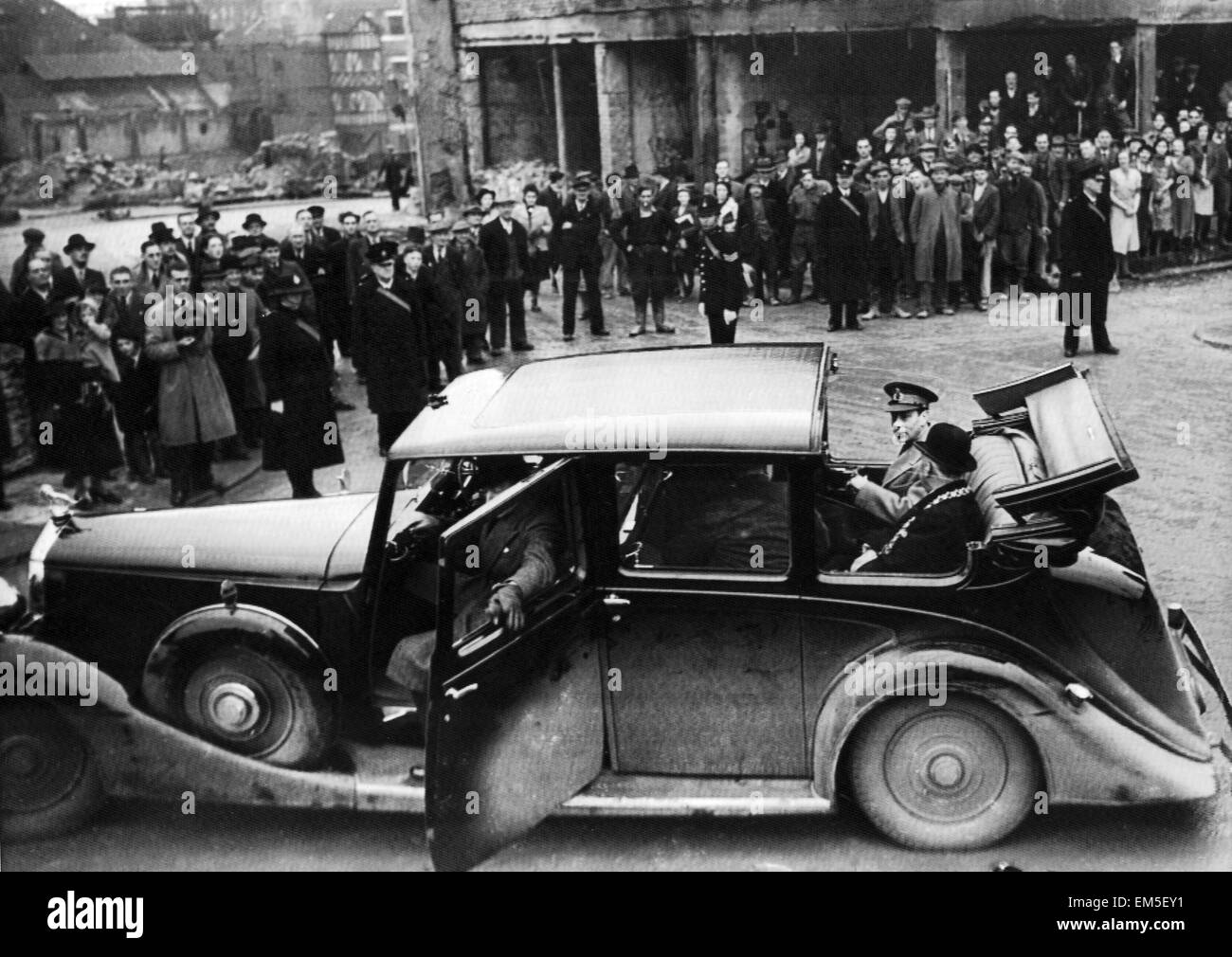 King George VI sits in the back of an open top car as he visits the bomb damaged city of Bristol following an air raid. December 1940. Stock Photo