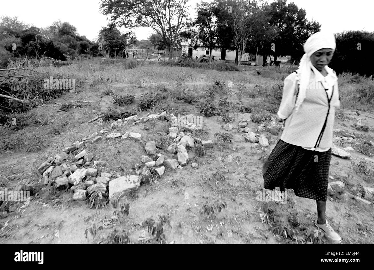 AIDS, poverty and drought in rural areas of Kenya. Kenyan woman. Her husband is buried in the garden. In Kitui families bury their dead within the limits of their homes. Lydia has to struggle to pull ahead the whole family. The priest of the Catholic Church Ikutha took pity on her and hired her as a caregiver school girls of the parish. Stock Photo