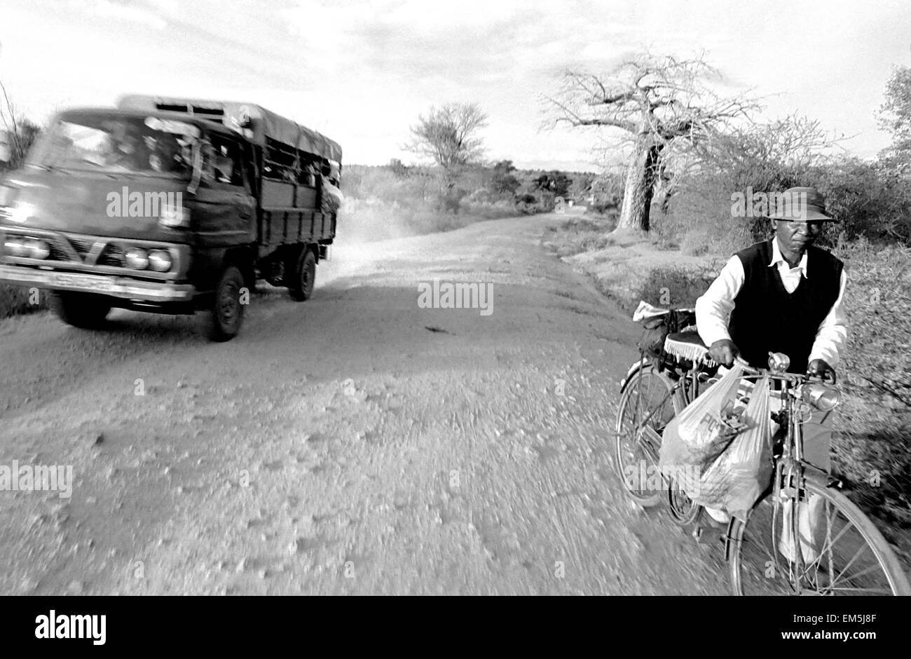 A matatu and a bicycle in a dusty road in rural Kenya. Landscape. The infrastructure in Kenya are very poor. The roads are not p Stock Photo