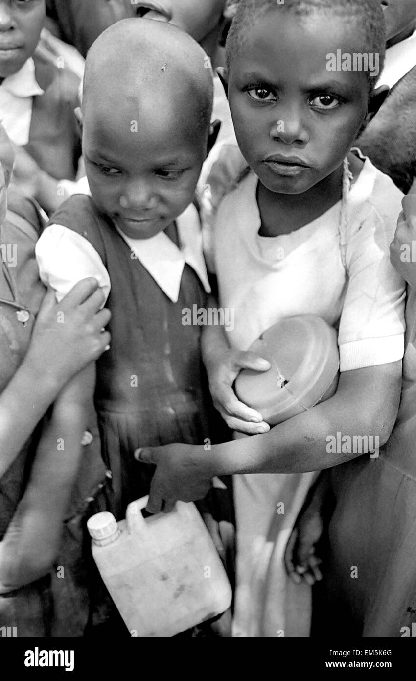 Two children eat in rural Kenya. Ikutha, Kitui, Kenya. Many children lack adequate food, such as proteins from red meat, milk or fish. Ikutha is a town from the Sub-Sahara Africa punished by whips of the AIDS, the lack of water and educative and sanitary resources. During years there is no development worked against zones more disadvantaged and the international aids have still not arrived at this zone. This rural locality has only around 500 inhabitants and is located in the heart of Kenya already worn away by a government who has corrupted it for more than 20 years. Stock Photo
